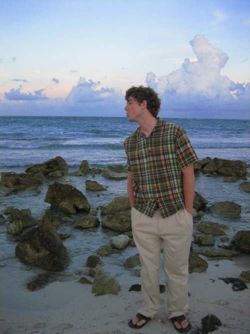 Man standing in the sand near the ocean water.