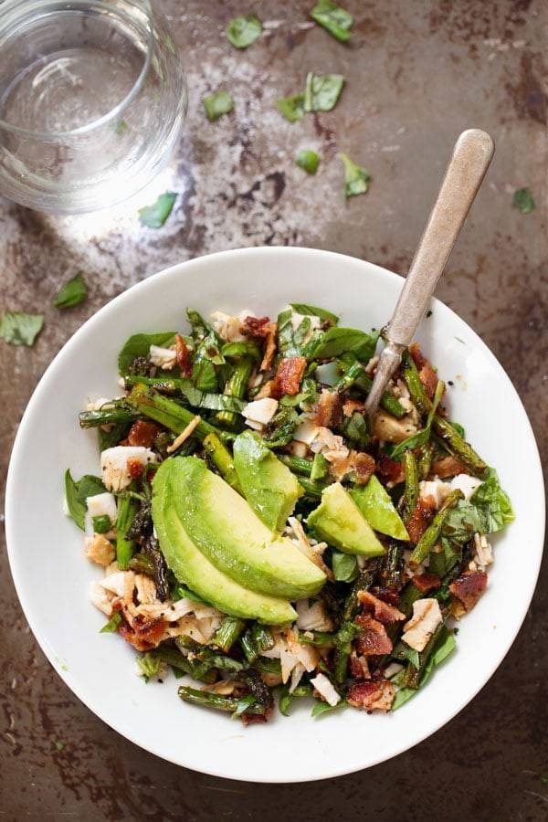 Chicken Bacon Avocado Salad with Roasted Asparagus in a white bowl.
