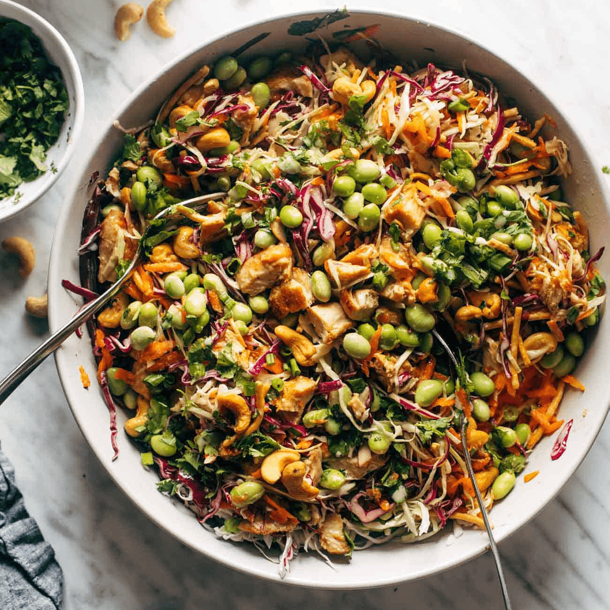 A spoon sits in a bowl cashew crunch salad.