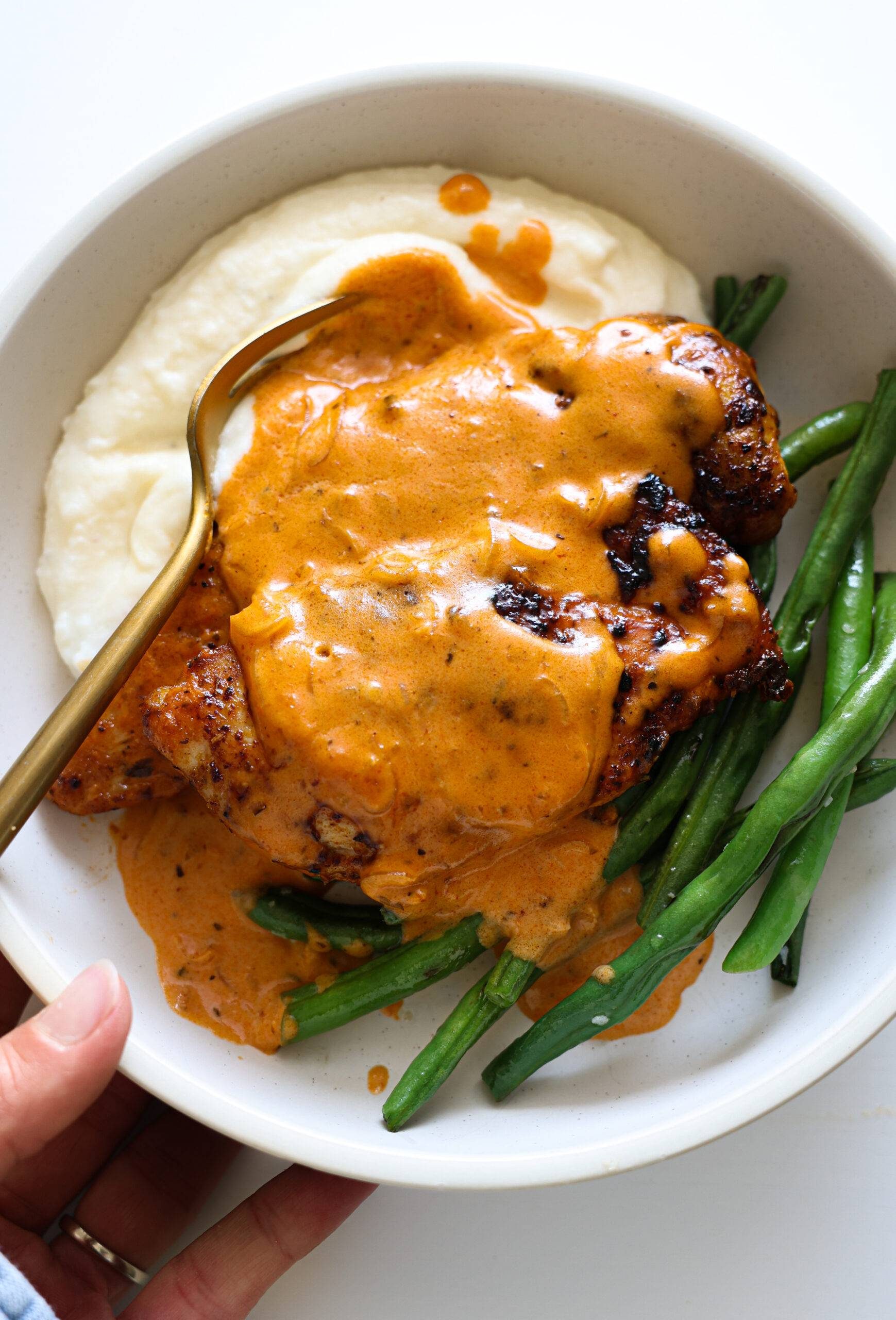 Chicken with creamy cajun sauce, on mashed potatoes with green beans, on a plate