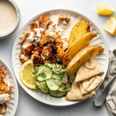 Chicken, potatoes, and cucumber salad on a plate.