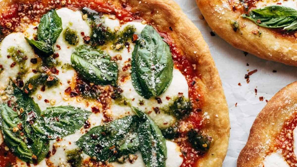Fried Pizzas on parchment paper with basil.