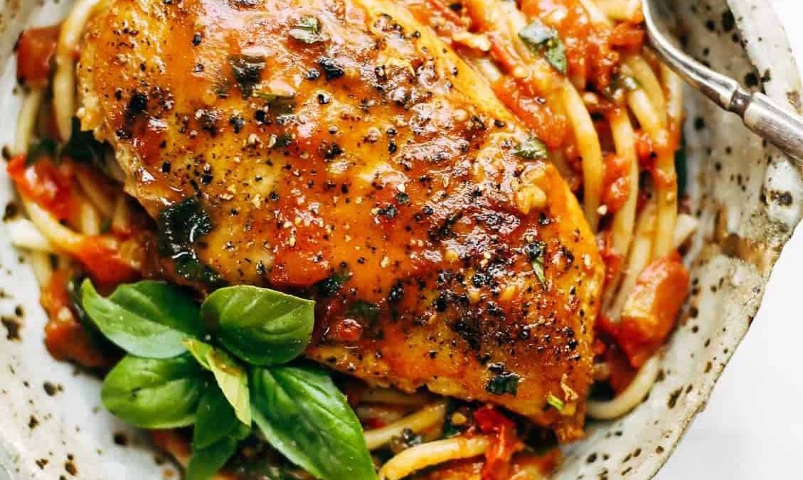 Garlic Basil Chicken in a bowl with pasta and basil.