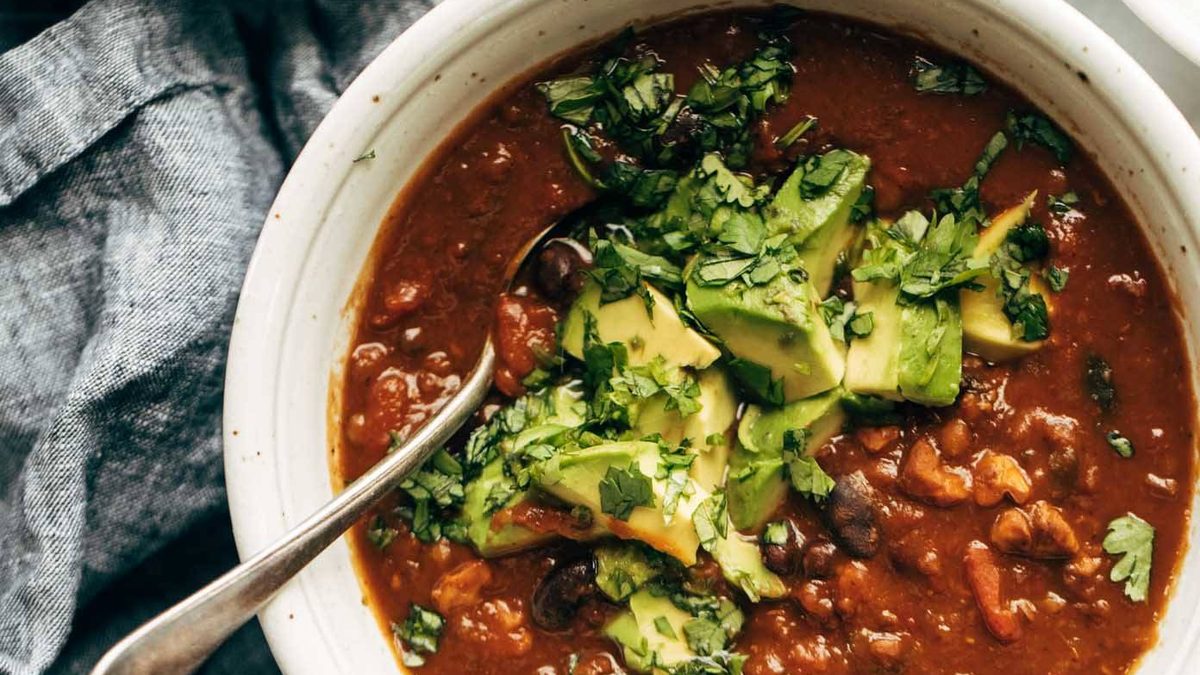 Chili in a bowl with a spoon and toppings.