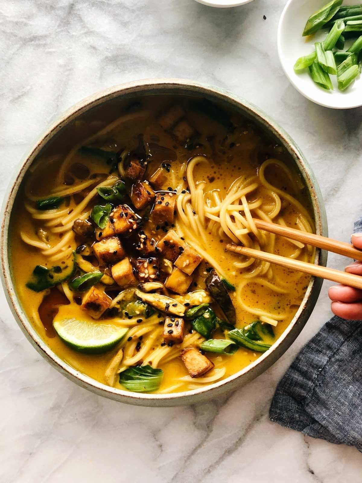 Soup with paneer, noodles, lime and with chopstick.
