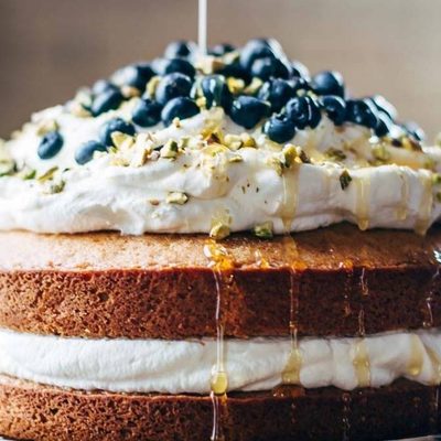 Blueberry Orange Brunch Cake on a cake stand with agave poured on it.