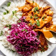 Peanut chicken on a plate with slaw and rice.