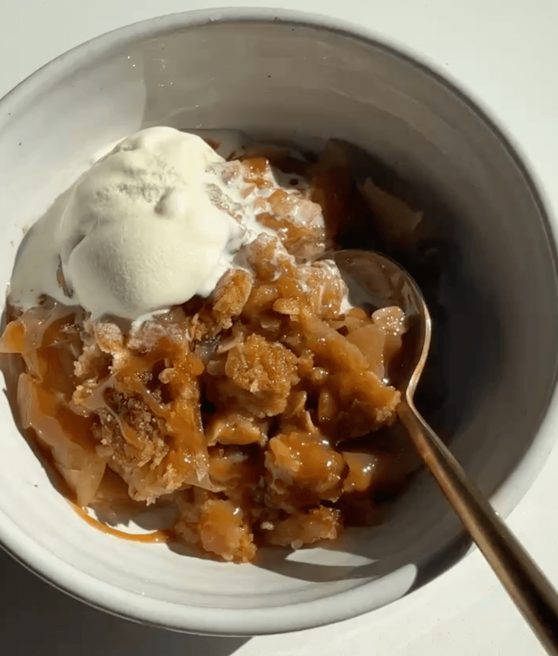 Apple crisp in a bowl with ice cream.