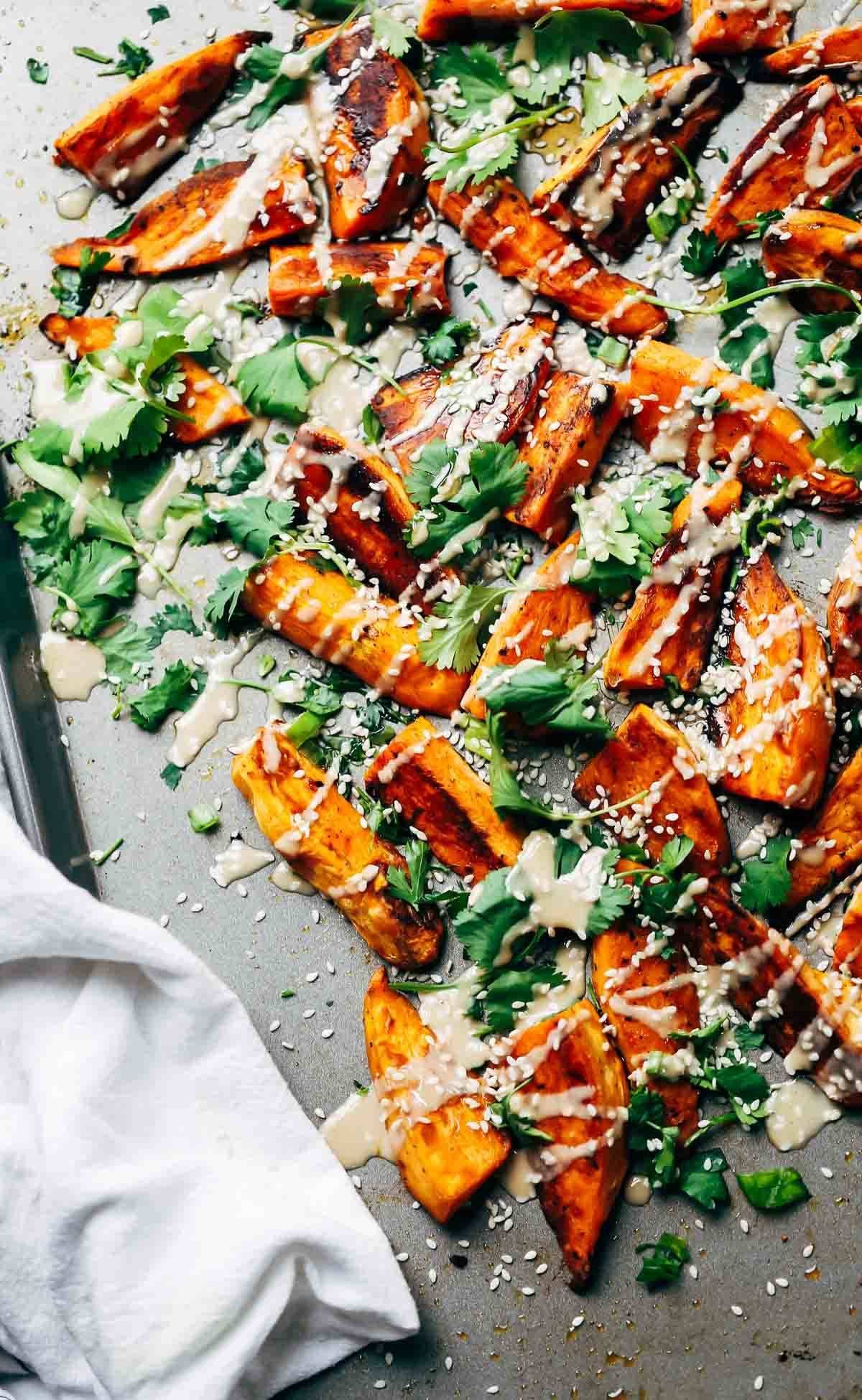 Sesame Roasted Sweet Potatoes topped with tahini, sesame oil, cilantro, and sesame seeds.