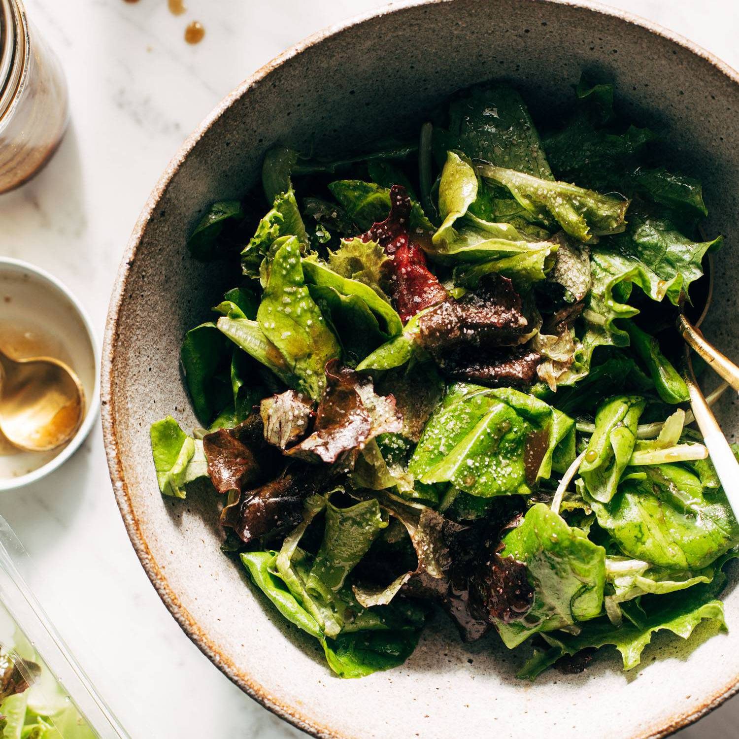 Green salad in a bowl with dressing on the side.