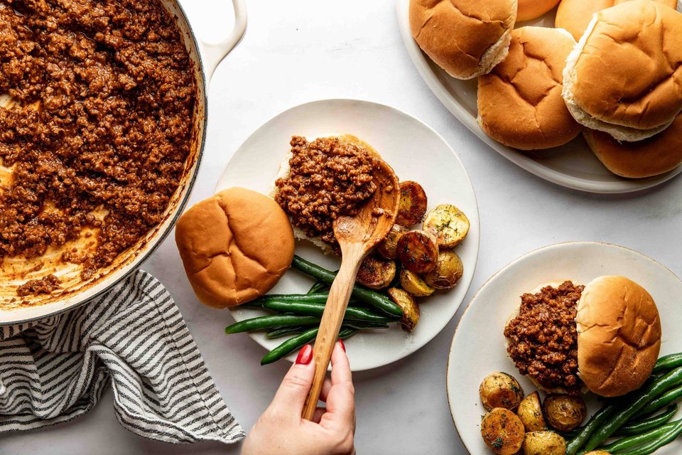 Serving sloppy joe on a plate with potatoes and green beans.