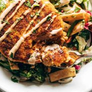 Salmon burgers on a bed of Mixed Greens in a bowl.