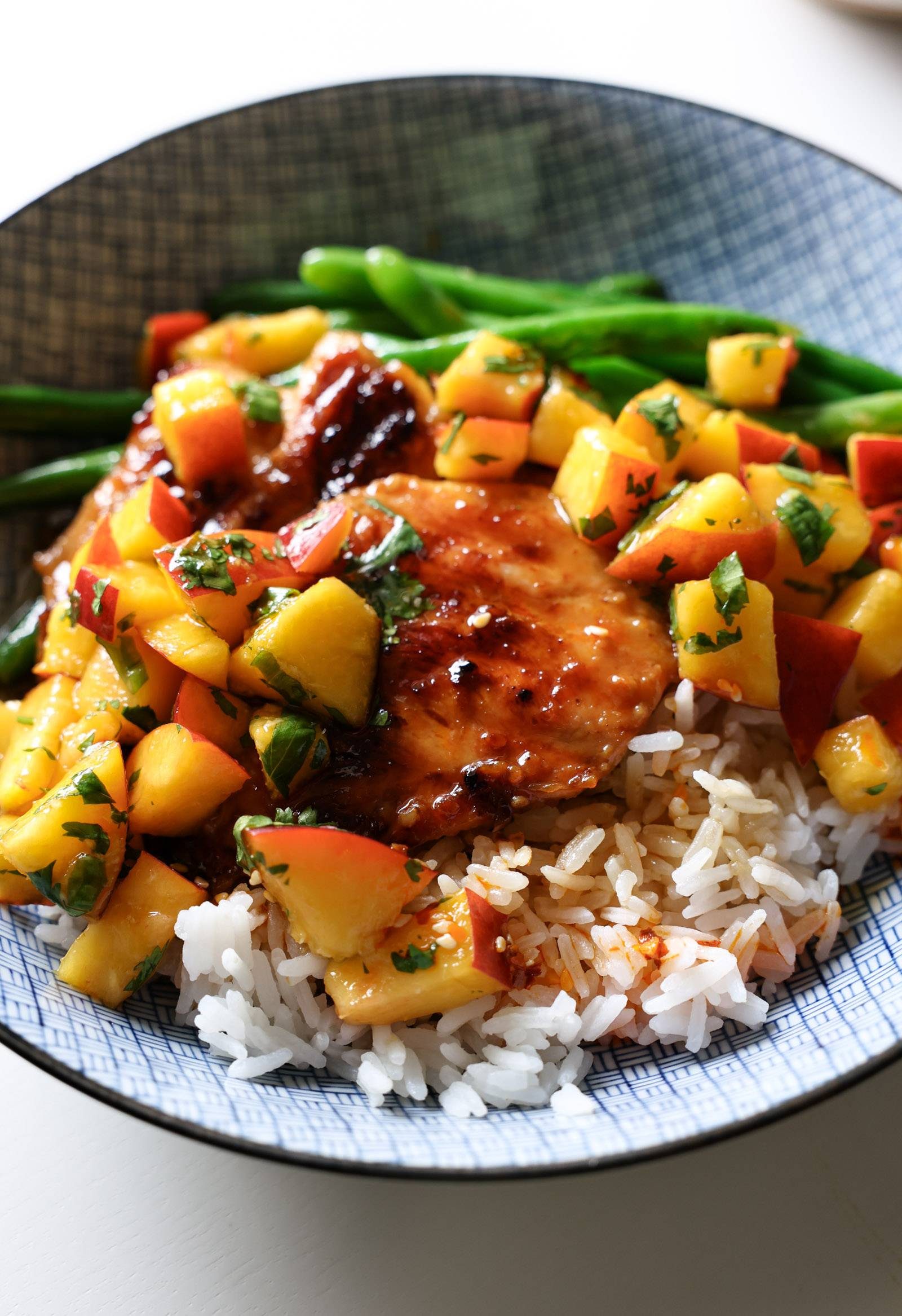 Teriyaki chicken in a bowl with peaches, rice, and green beans.