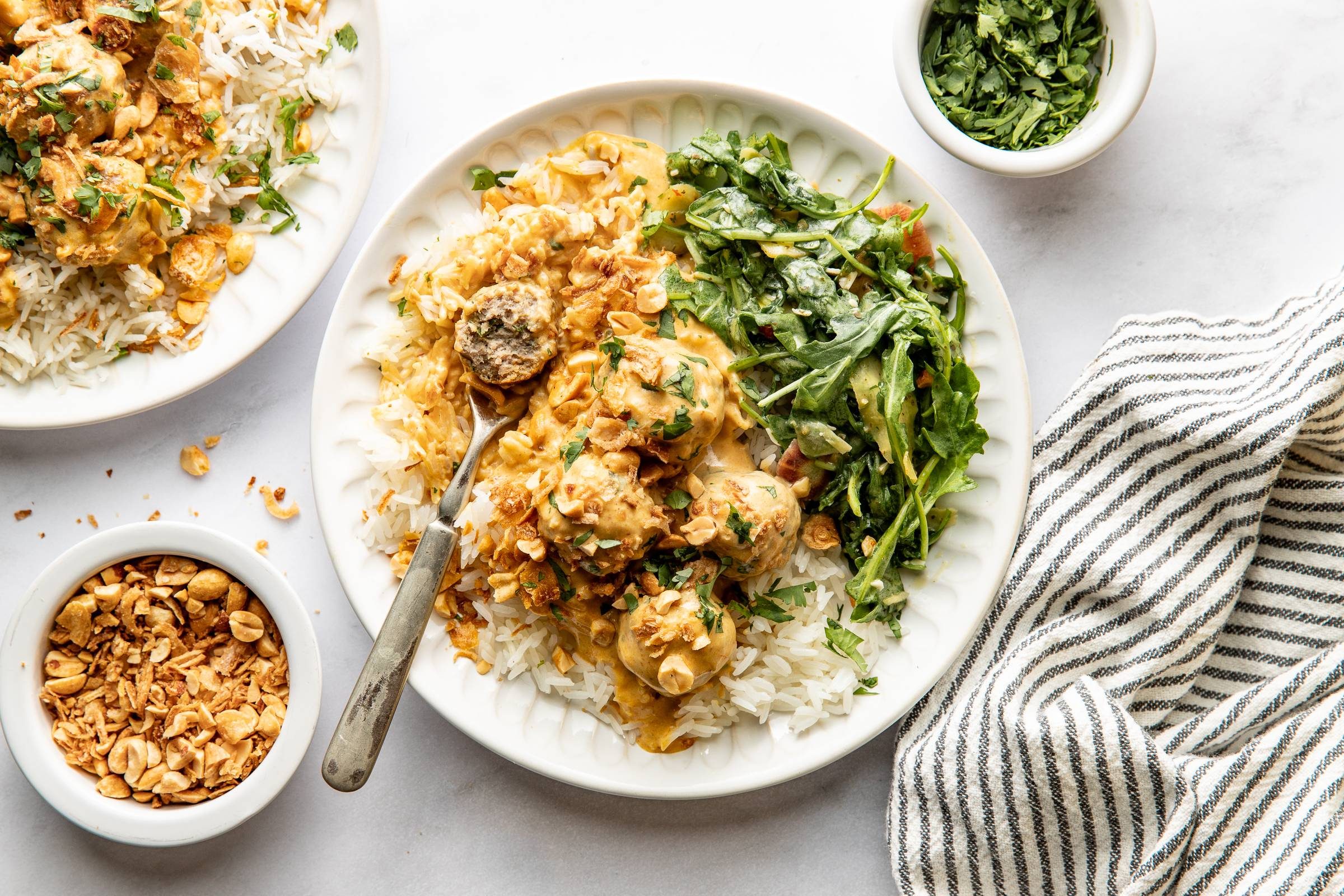 Finished meatballs on a plate with rice and greens.