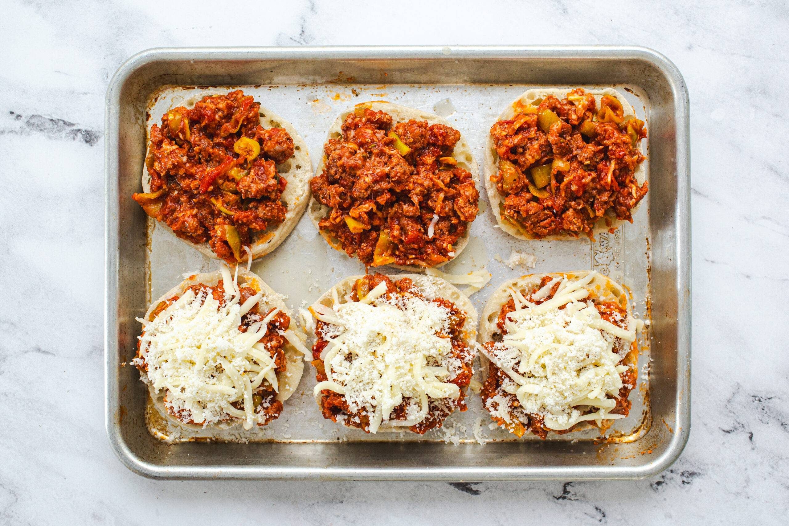 Pizza burgers with cheese on top before baking.