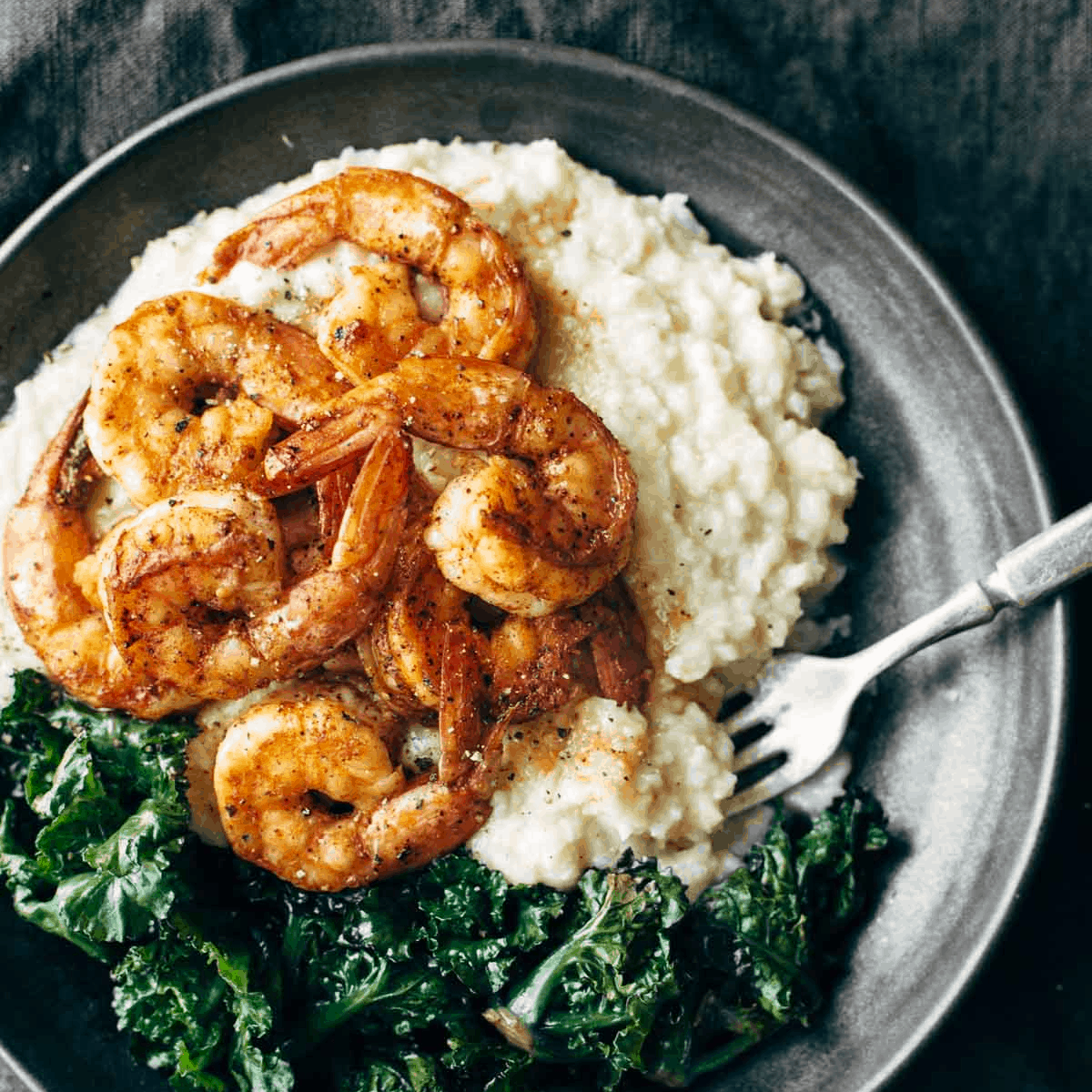 Spicy shrimp and cauliflower mash on a plate with kale.