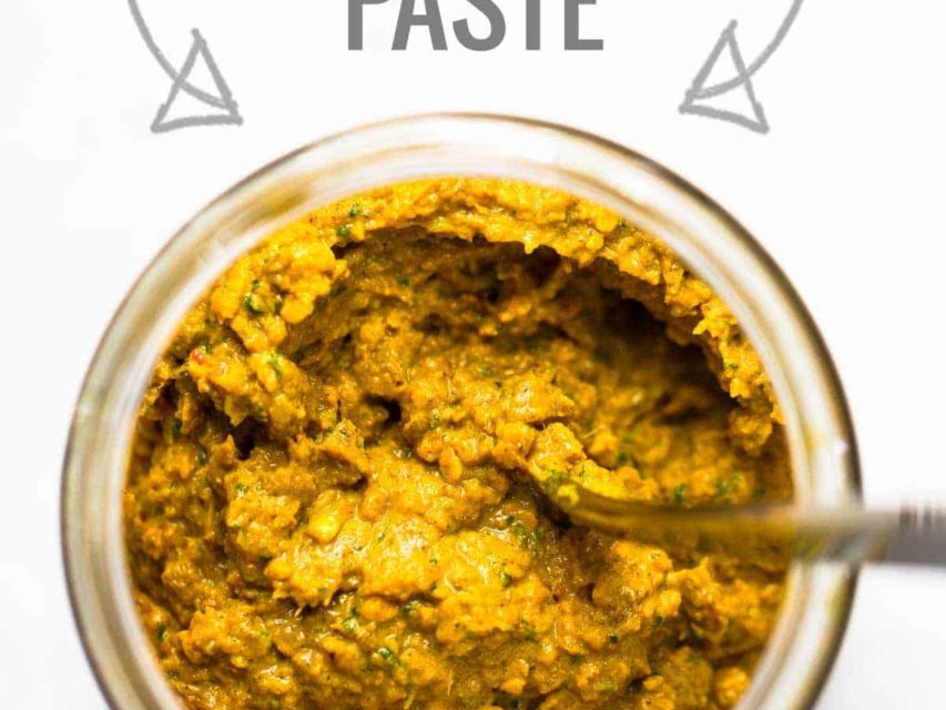 Homemade yellow curry paste in a jar with a spoon.
