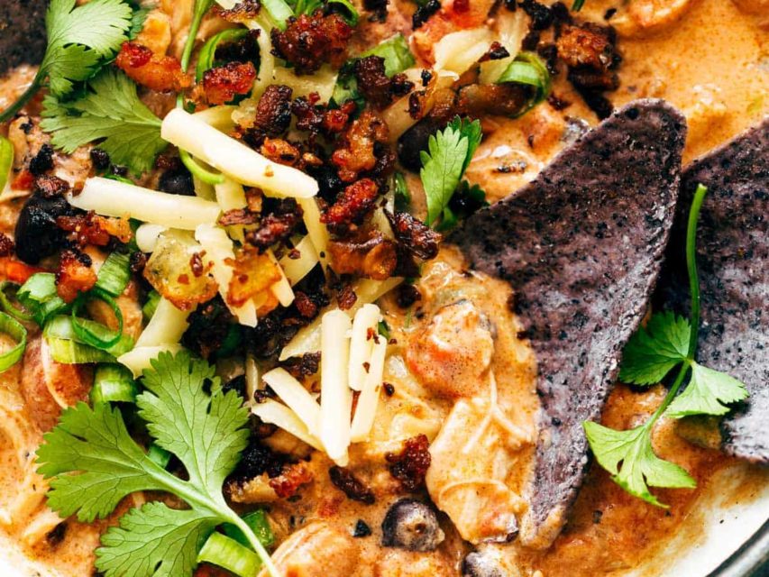 Chips in a bowls of chili and garnishments.