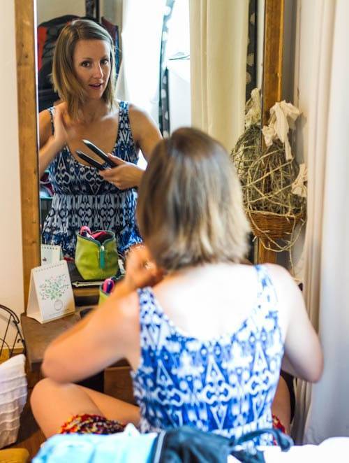 Woman straightening her hair in a mirror.