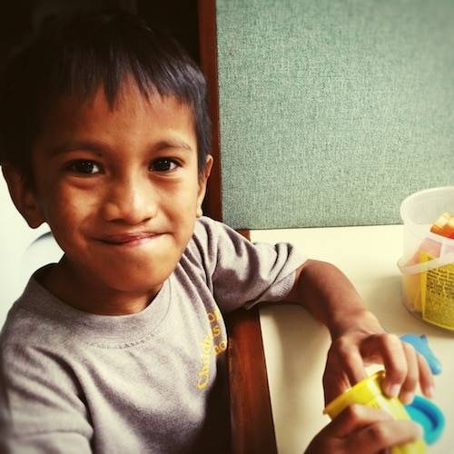 Young boy smiling while playing with play dough.