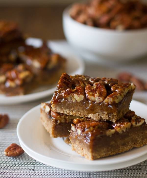 Salted maple pecan pie bars stacked on a white plate.