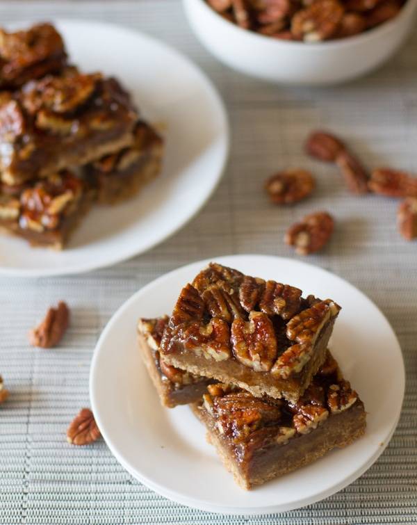 Salted maple pecan pie bars on plates with pecans.
