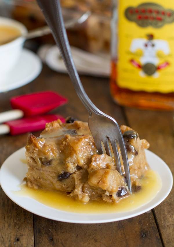 Bread pudding with hot butter rum sauce on a plate with a fork.