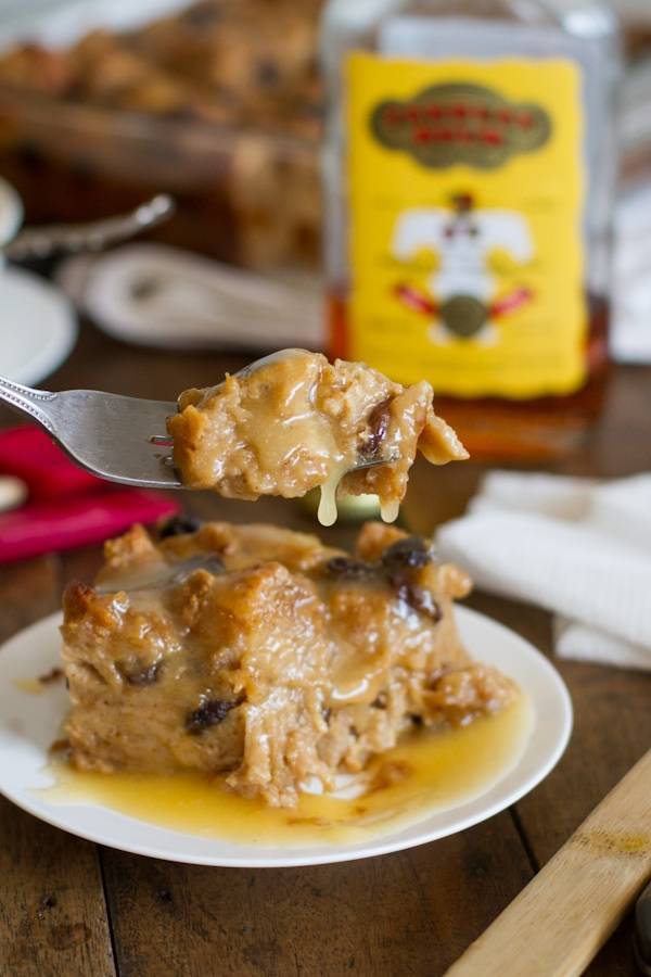 Bread pudding with dripping hot butter rum sauce on a plate and a fork.