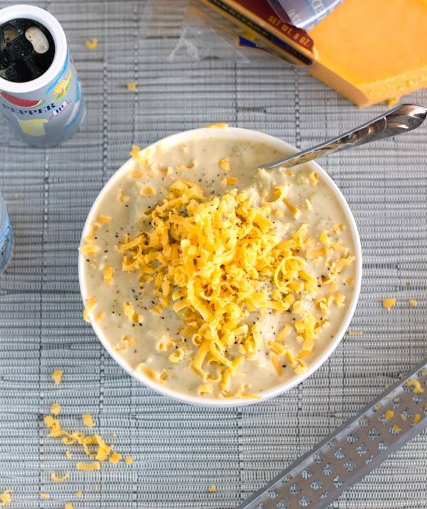 Crockpot Broccoli Cheese Soup in a bowl with cheese topping and a spoon.