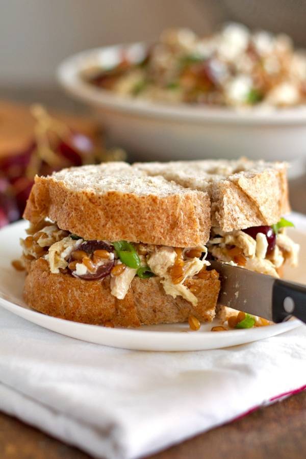 Sandwich filled with honey chicken salad with grapes and feta.