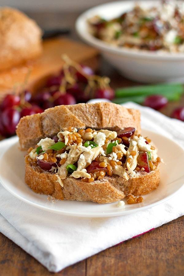 Honey chicken salad with grapes and feta between two pieces of bread.