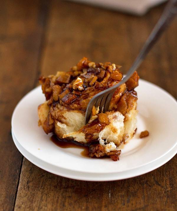 Slice of homemade caramel rolls topped with walnuts.