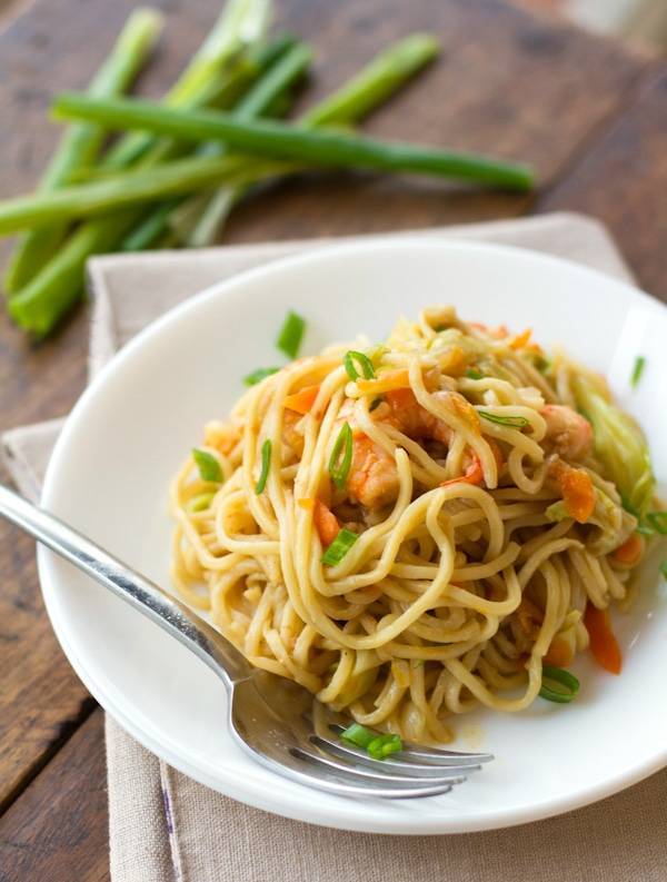 Stir fried noodles with shrimp and vegetables on a plate with a fork.