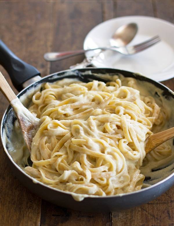 Alfredo with cauliflower sauce in a skillet with wooden spoons.