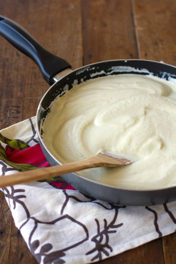 Creamy cauliflower sauce in a skillet with a wooden spoon.