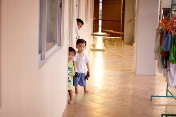 Young children peeking out of a door way.