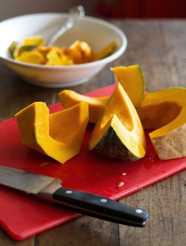 Slices of kabocha squash on a red cutting board.