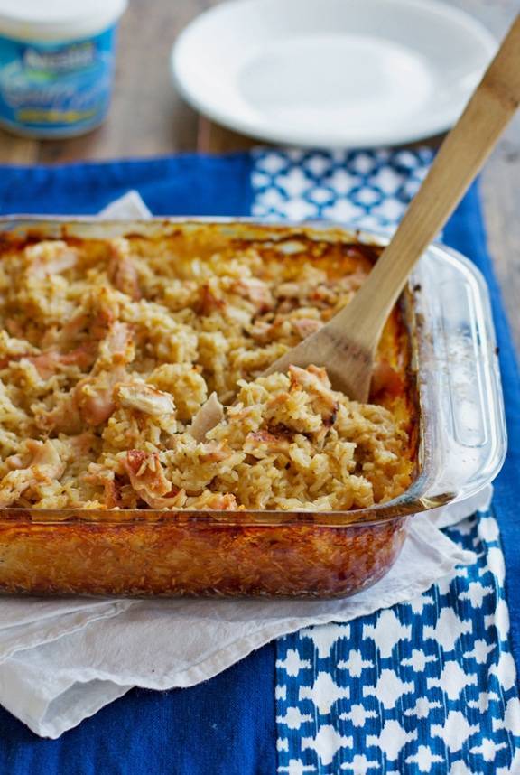 Chicken and rice casserole in a baking dish with a wooden spoon.