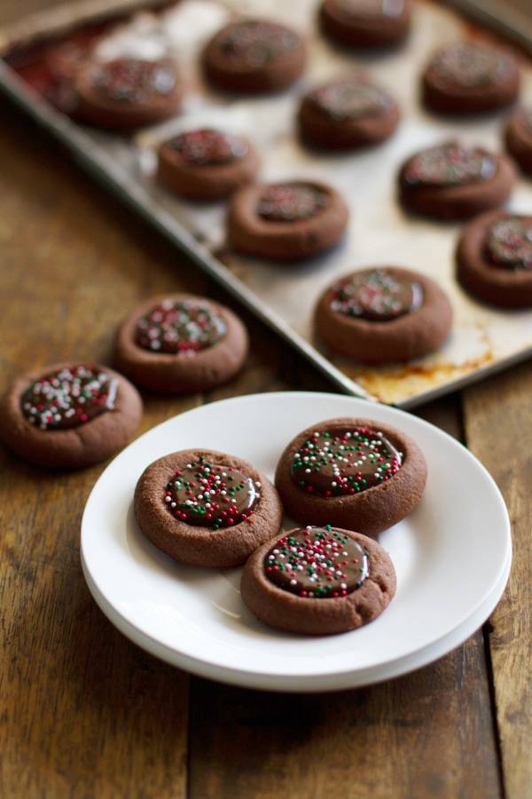Chocolate thumbprint cookies on a white plate.