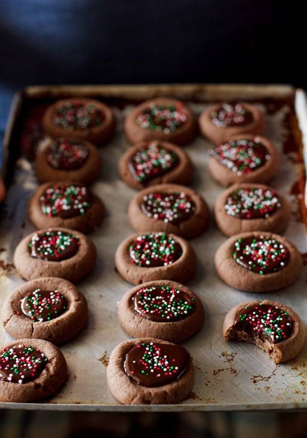 Chocolate thumbprint cookies with sprinkles on a baking pan.