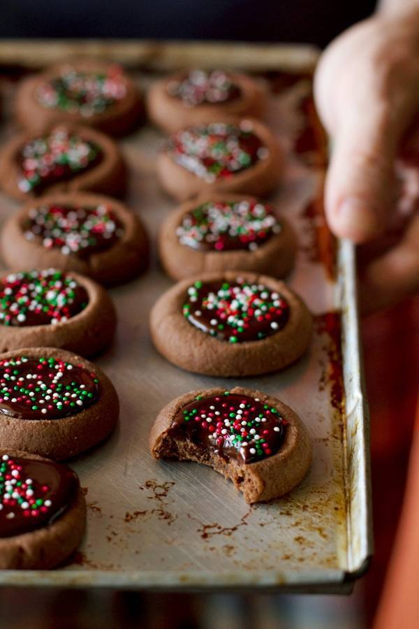 Chocolate thumbprint cookies with sprinkles on a baking pan.