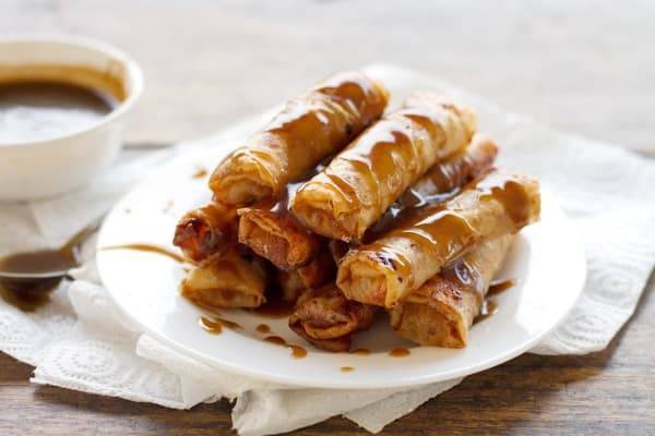 Banana lumpia drizzled with caramel on a white plate.