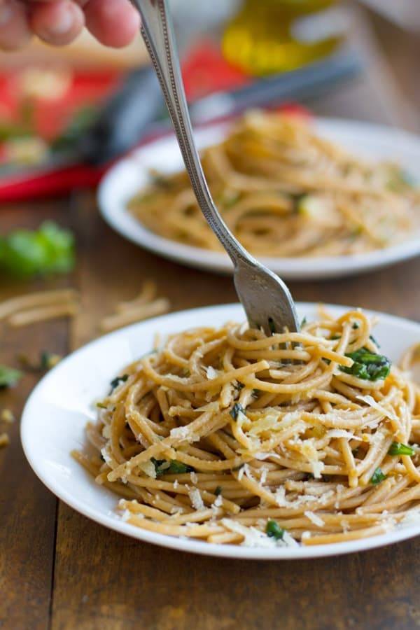 Garlic butter spaghetti with herbs on a white plate with a fork.