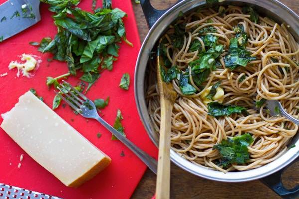 Garlic butter spaghetti with herbs in a pot and on a cutting board.
