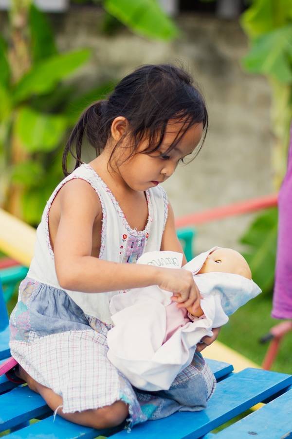 Young girl playing with a baby doll.