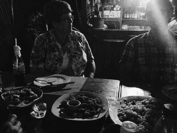 Black and white photos of people sitting at a table.