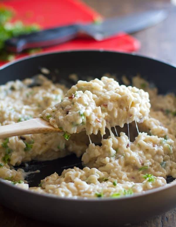 Creamy cauliflower sauce over grains in a skillet on a wooden spoon.
