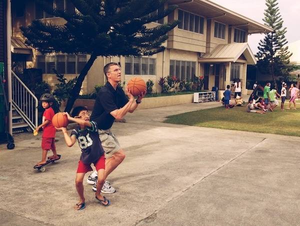 Man playing basketball with young boy.