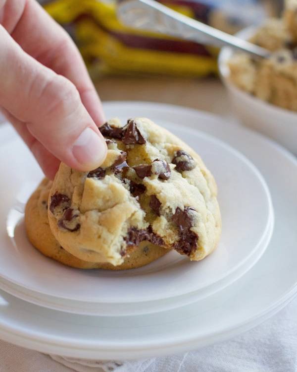 Fingers pulling apart a chocolate chip cookie.