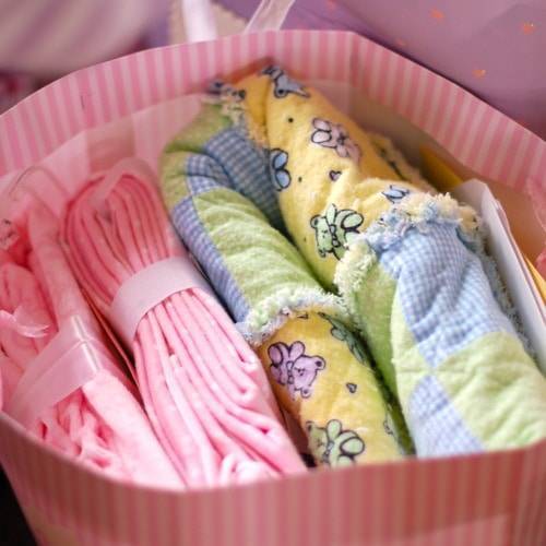 Baby blankets and clothing in a pink gift bag.